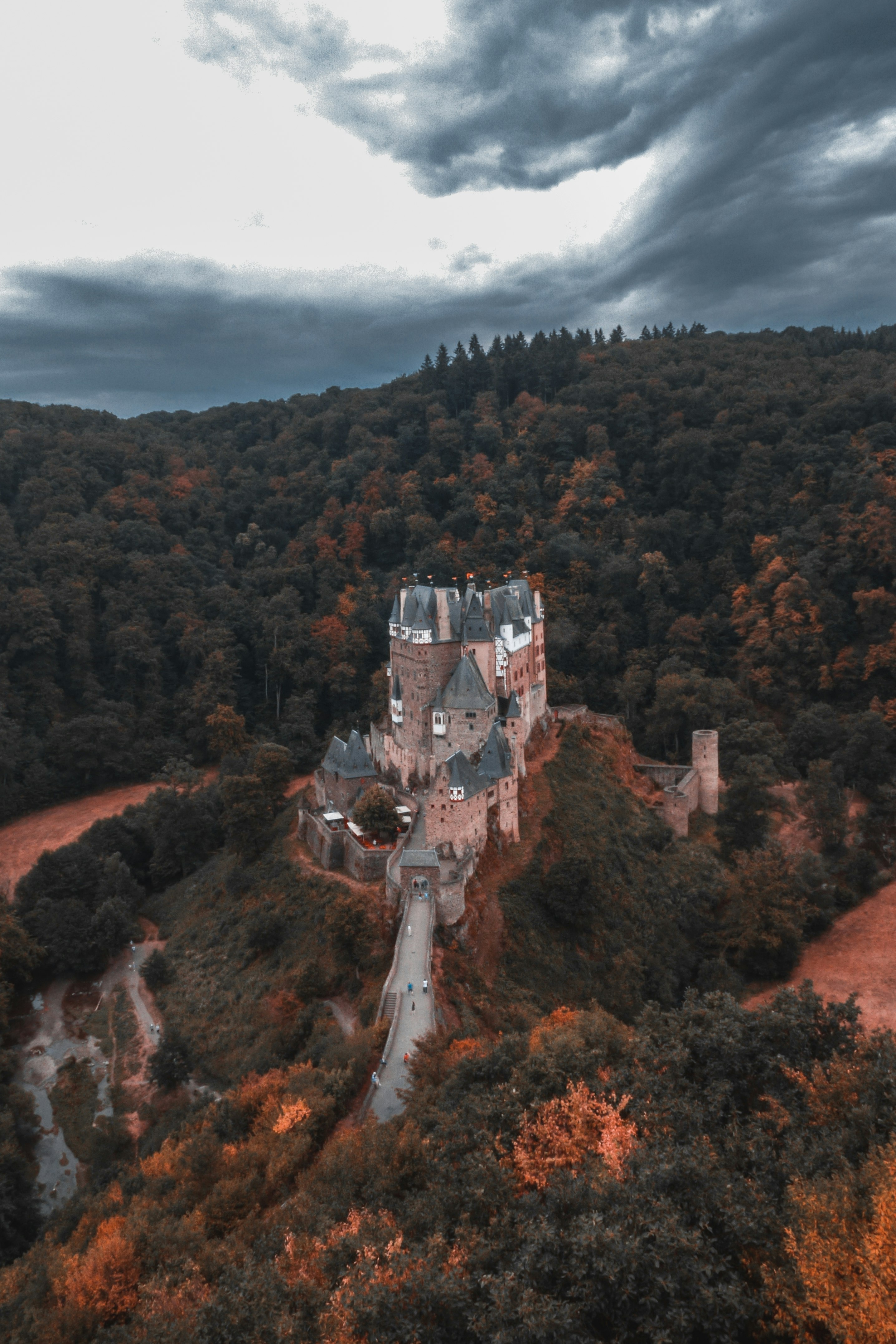 concrete castle surrounded with trees under gray and white clouds during daytime